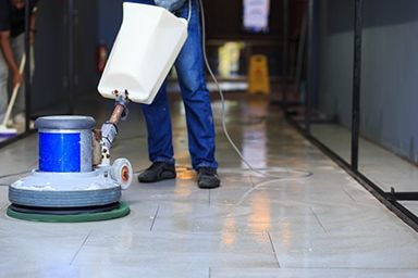 Worker pouring cleaning solution into floor machine